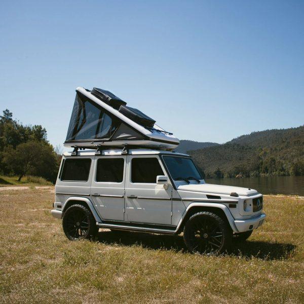 Home 7 Aerodynamic wedge hard shell roof top tent deployed, featuring integrated cargo crossbars for extra gear storage.