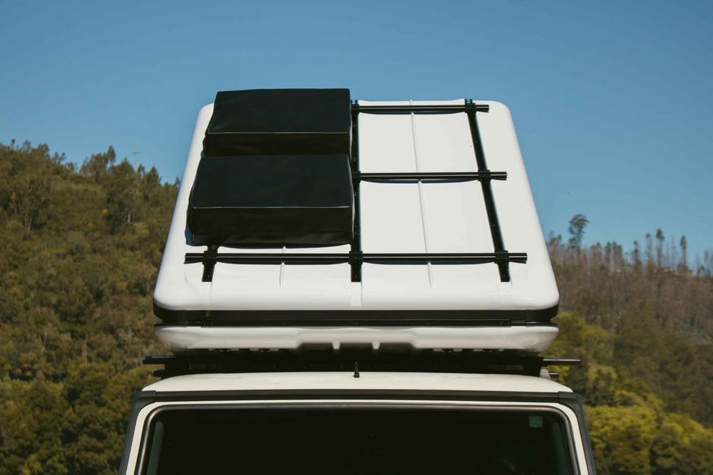 Fully deployed wedge roof top tent supporting attached cargo gear on the shell, demonstrating powerful hydraulic strut capacity.