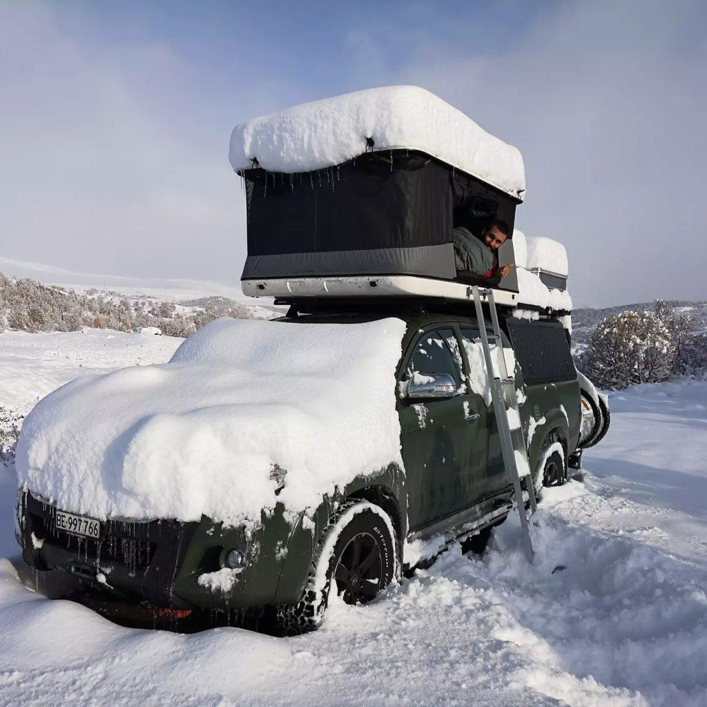 Heavy-duty fiberglass hard shell roof top tent withstanding thick snow load, demonstrating 4-season thermal insulation and extreme weather durability.