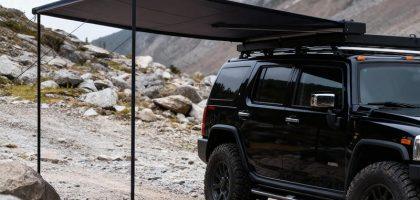 Side profile view of the deployed auto-roll car awning, showing the sturdy aluminum legs and full extension range.